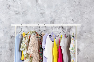 Canvas Print - Women's hip clothing store interior concept. Row of different colorful female clothes hanging on rack in hipster fashion show room in shopping mall. Grunged concrete wall background. Copy space.