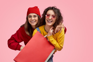 Wall Mural - cheerful friends hugging during shopping