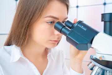 Sticker - Young woman technician is examining a histological sample, a biopsy in the laboratory of cancer research