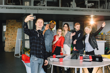 Wall Mural - Positive group of business people making selfie in modern office. Group of six hipster workers making selfie after meeting