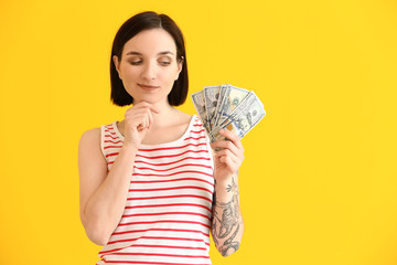 Thoughtful young woman with dollar banknotes on color background