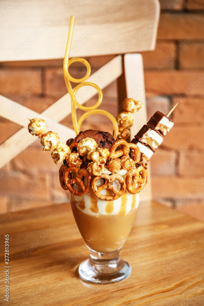 Delicious freak shake on wooden chair against brick background