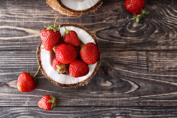 Coconut with ripe red strawberry on wooden background