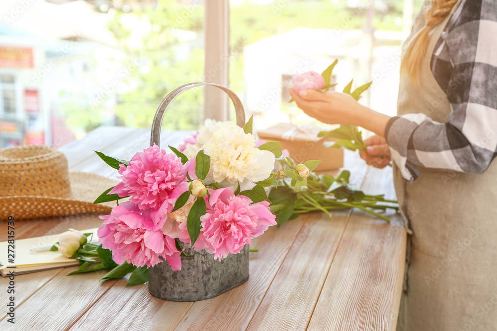 Watering can with beautiful peonies on table of florist