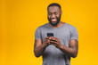 © denis_vermenko - Portrait of handsome excited cheerful joyful delightful curious guy wearing casual sending and getting messages to his lover isolated against yellow background. Using phone.