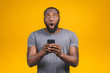 © denis_vermenko - Great news! Portrait of handsome excited cheerful joyful delightful curious guy wearing casual sending and getting messages to his lover isolated against yellow background. Using phone.