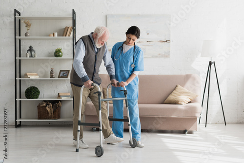 Fotomural Nurse helping to senior man walking at home, recovering after injury