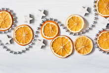 Christmas Composition With Dried Oranges, White Stars And Silver Bead Chain - White Background With Deep Shadows - Close-up