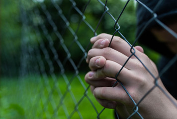 young unidentifiable teenage boy holding the wired garden praying at the correctional institute , co