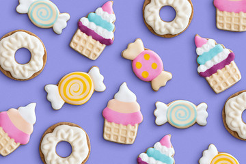 Cookies variety pattern on a pastel background. Various cookie shapes (cupcake, candy, donut). Top view.