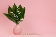 Bouquet of lilies of the valley in a pink vase on a pink background