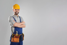 Portrait Of Professional Construction Worker With Tool Belt On Grey Background, Space For Text