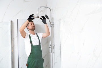 Poster - Professional handyman working in shower booth indoors, space for text