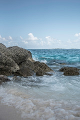 Wall Mural - GENTLE WAVES CRASHING AGAINST ROCKS AT THE BEACH