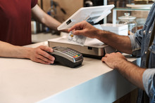 Cropped Photo Of Caucasian Man Paying Debit Card In Cafe While Waiter Holding Payment Terminal
