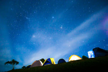 Illuminated Camping Tents Under Starry Night Sky.