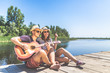 © zphoto83 - Beautiful couple sitting on pier with acoustic guitar and singing song. Love, music and nature concepts.