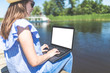 © zphoto83 - Beautiful hipster girl sitting on dock and working on laptop. Lake or river in the background. Work and travel concept.