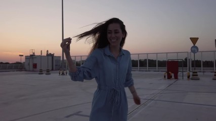 Wall Mural - Happy young woman on parking level in the city at sunset