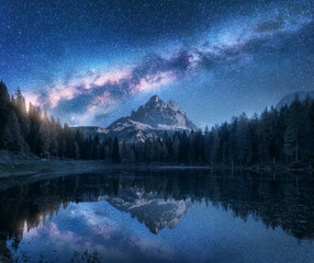 Milky Way over Antorno lake at night. Summer landscape with alpine mountains, trees, blue sky with milky way and stars, beautiful reflection in water, high rocks. Dolomites, Italy. Space and nature