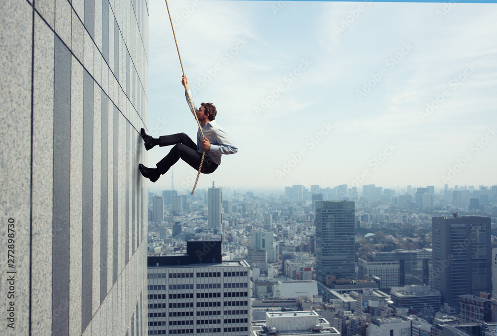 Businessman climbs a building with a rope. Concept of determination - obrazy, fototapety, plakaty 