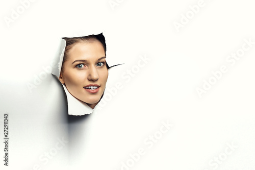 Cuadros en Lienzo Woman looking out from a hole of torn paper