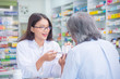 Beautiful asian Pharmacist explaining the pills to patient in drug store