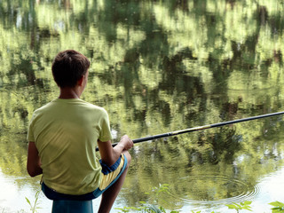 teen child catches a fishing rod on the pond.