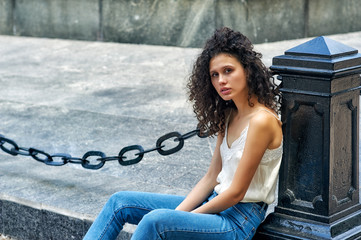 Portrait of a young girl in the city . Slim model in jeans and light blouse