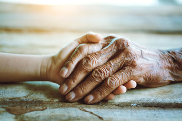 Hands of the old man and a child's hand on the wood table