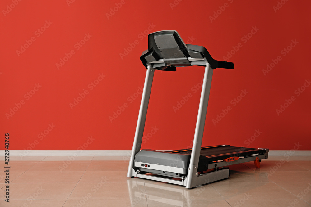Modern treadmill near color wall