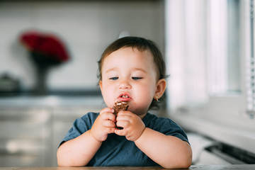 little girl in the afternoon in the kitchen eating a delicious chocolate bar