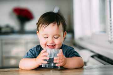 Cute little girl sitting in baby chair and drinking water