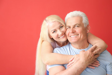 Wall Mural - Portrait of happy mature couple on color background