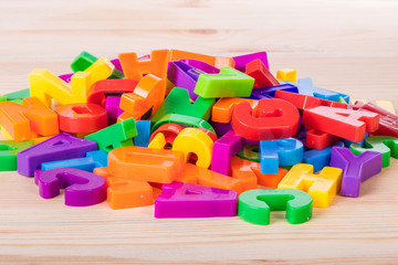 A pile of coloured magnetic letters over a school wooden table