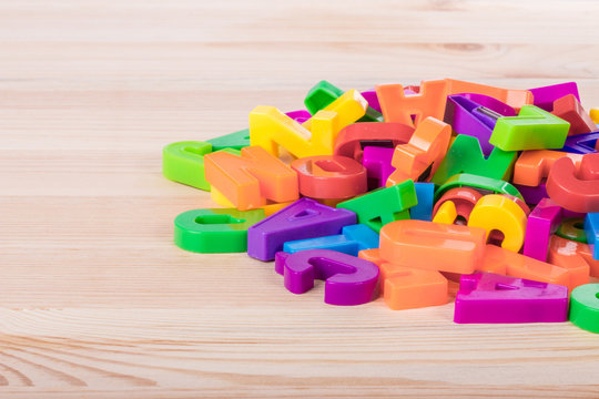 A pile of coloured magnetic letters over a school wooden table