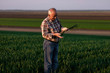 © Zoran Zeremski - Portrait of senior farmer standing in young wheat field holding crop in his hands.