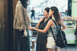 © PR Image Factory - Two female shopaholic friends gazing at lady clothes wear on dummy model. sisters spend leisure time on weekend buying dress prepare for coming summer. women touching discussing about shirt hong kong