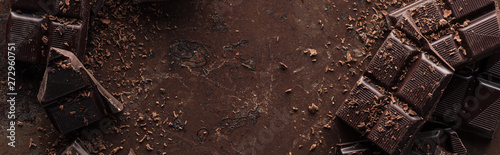 Fotomural Panoramic shot dark chocolate bar with chocolate chips on metal background