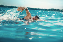 Professional Triathlete Swimming In River's Open Water. Man Wearing Swim Equipment Practicing Triathlon On The Beach In Summer's Day. Concept Of Healthy Lifestyle, Sport, Action, Motion And Movement.