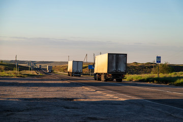 Wall Mural - Trucks with closed trailers carry goods between cities