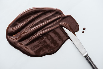 Wall Mural - Top view of table knife with melted dark chocolate