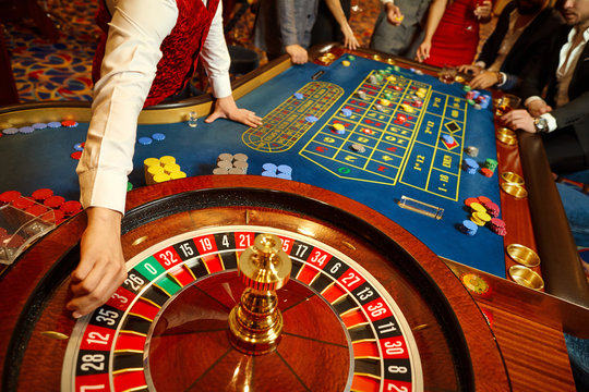 the croupier holds a roulette ball in a casino in his hand.