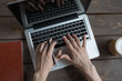 © DmitryStock - man works with a laptop at a wooden table with a cup of coffee and a diary. Holds a black pen in hand