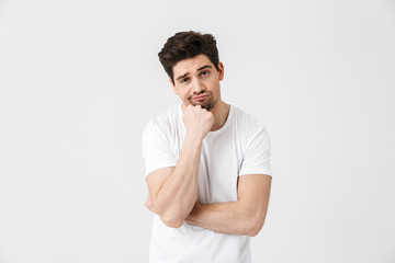 Canvas Print - Tired bored young man posing isolated over white wall background.