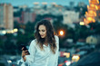 © paffy - Young woman over cityscape holding a smart phone texting