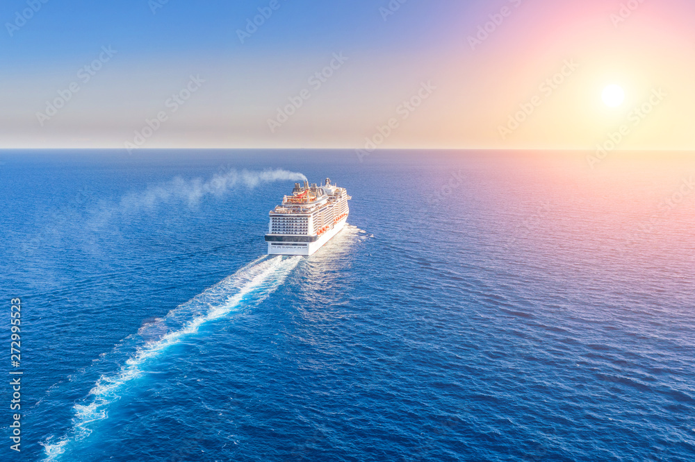 Cruise ship liner goes into horizon the blue sea leaving a plume on the surface of the water seascape during sunset. Aerial view, concept of sea travel, cruises. - obrazy, fototapety, plakaty 