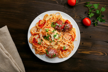 Wall Mural - Plate of spaghetti with meatballs, parmesan and tomato sauce on a rustic wooden table. Tasty Italian pasta food. Top view shot directly above.