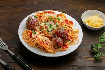 Wall Mural - Plate of spaghetti with meatballs, parmesan and tomato sauce on a rustic wooden table. Tasty Italian pasta food.