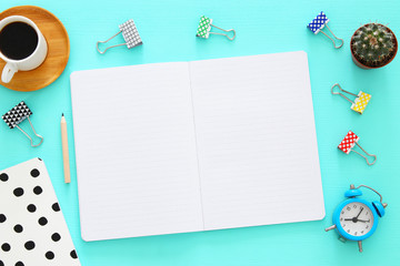 Open notebook with empty pages and other office supplies over blue office desk table. Top view